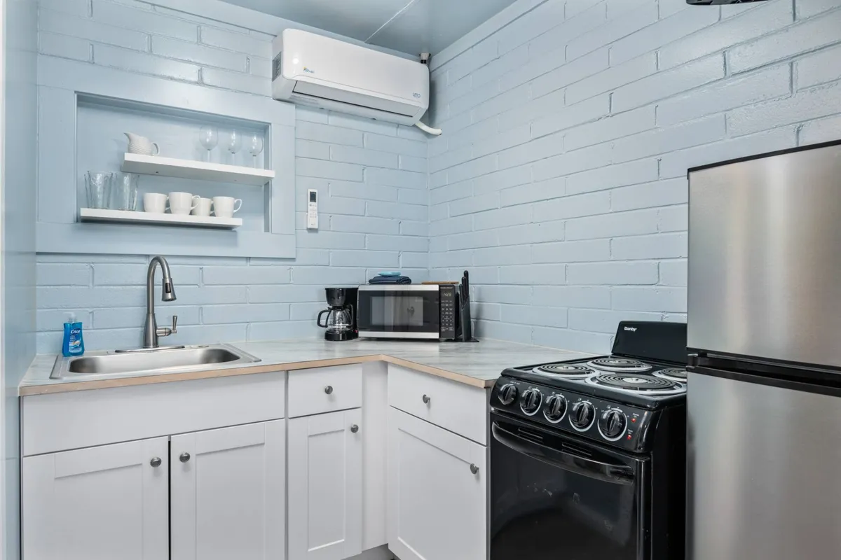 This image captures the heart of the kitchenette, showcasing the sink, stove, microwave, and refrigerator all within easy reach. The setup looks inviting and practical, perfect for preparing anything from a quick breakfast to a simple dinner after a day out.