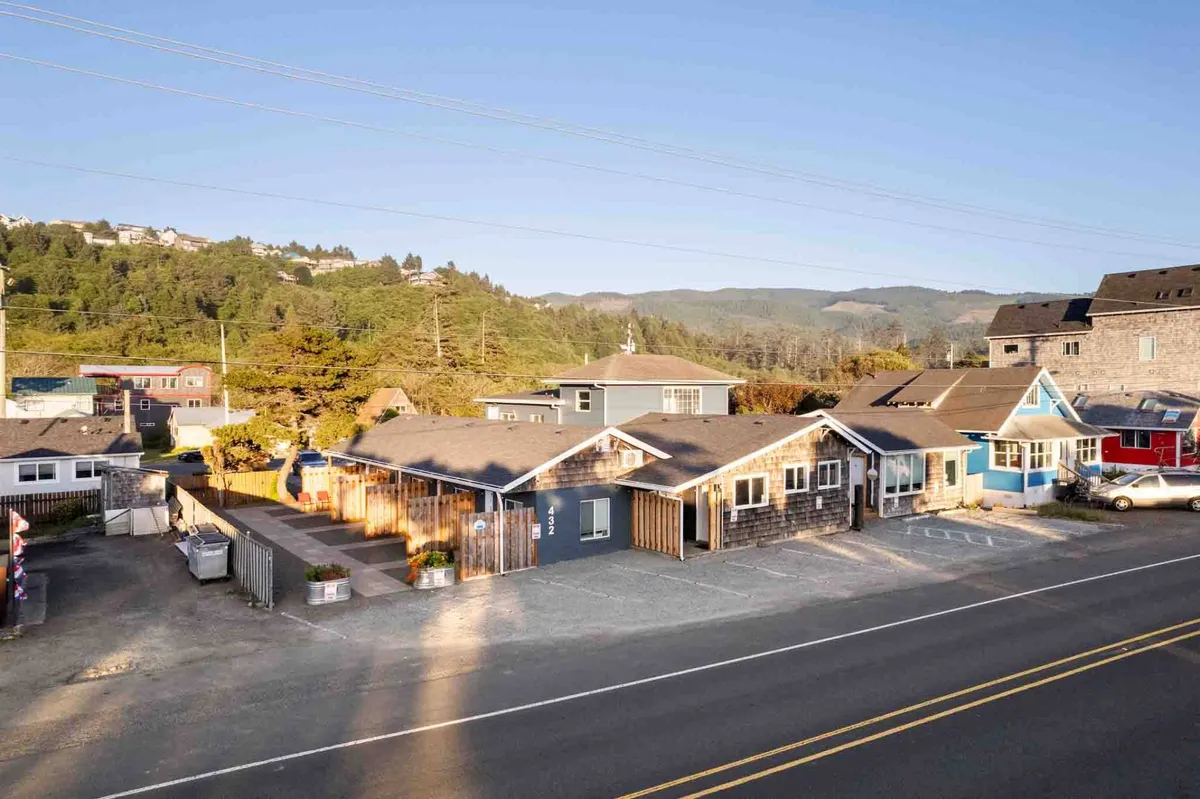 This relaxed exterior view highlights a collection of colorful houses surrounded by greenery and a parking area. The scene is lively, with people walking and exploring, suggesting an active neighborhood full of local flavor and social opportunities.